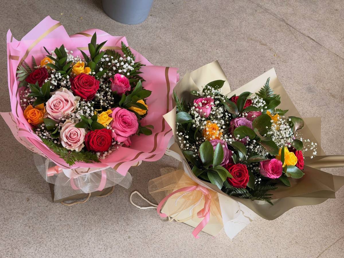 Two wrapped bouquets of roses and mixed flowers